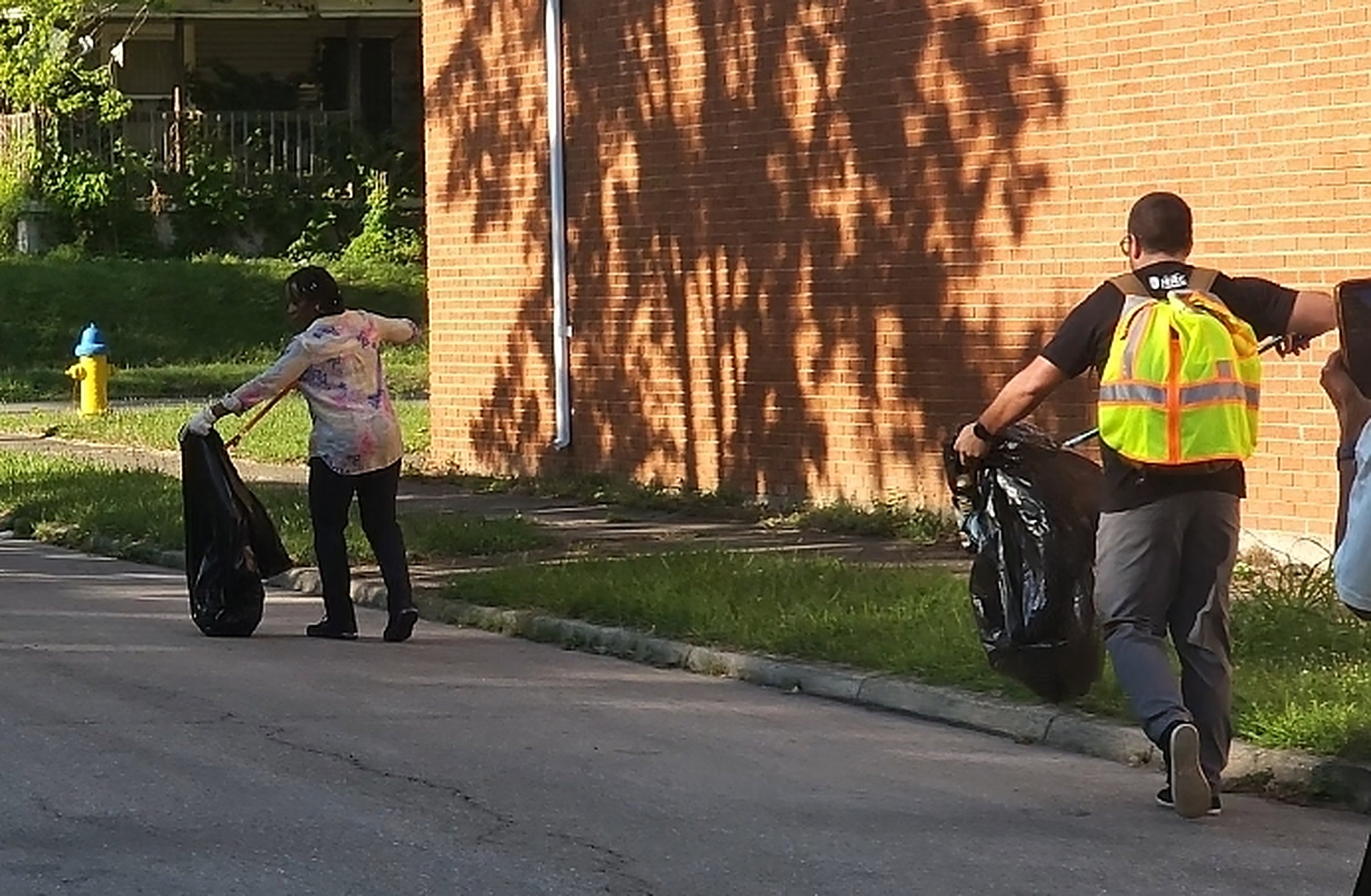 Two Do Not Be A Litterbug volunteers walking a Dayton street with trash bags on a summer clean-up