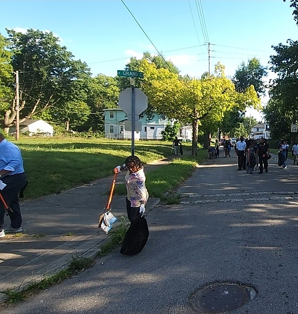 A Do Not Be A Litterbug volunteer sweeping and clearing a Dayton street during a clean-up